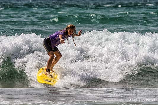 Surferin auf einem gelben Surfbrett beim Wellenreiten am Atlantik, hält die Balance auf einer Welle, am Strand von Biarritz, Côte des Basque 2012