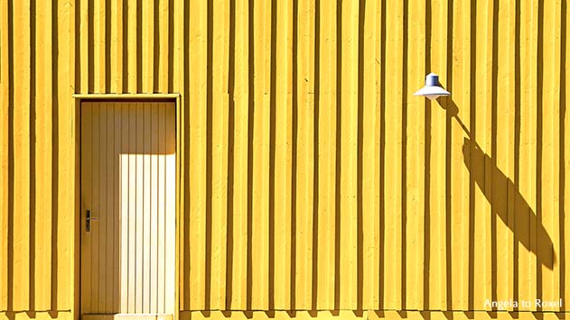 Fotografie: Tür und Lampe eines gelben Strandhäuschens auf der Île d’Oléron, leuchtendes Gelb, Architektur Bilder kaufen | Angela to Roxel