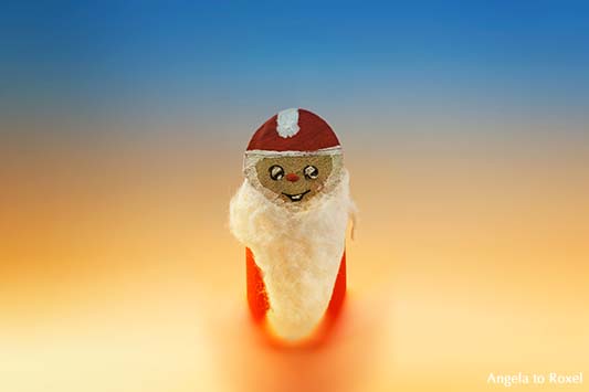 Fotografie: Kleiner Weihnachtsmann, aus einem Holzstück gebastelt, nicht größer als ein kleiner Finger, lächelt - Weihnachtsdekoration, Stockfoto