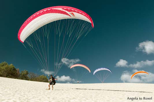 Ein Paraglider auf der Dune du Pilat beim Küstenstart, drei weitere Gleitschirme im HIntergrund