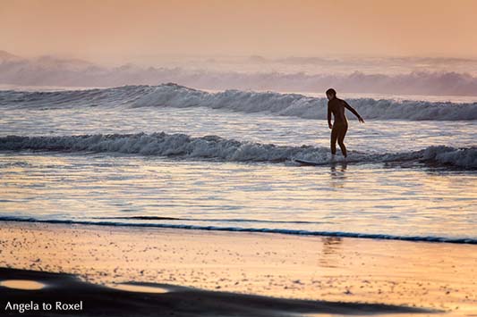 Silhouette einer Surferin in den auslaufenden Wellen der Brandung am Abend, Essaouira