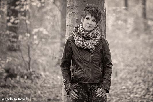 Frau an einem Baum im Herbstwald, monochrom