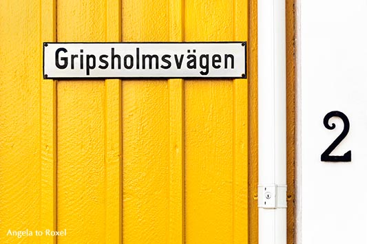 Straßenschild Gripsholmsvägen, an einem gelbweiß gestrichenen Schwedenhaus