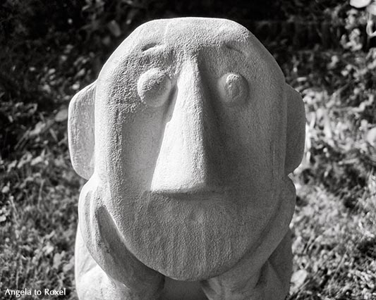 Fotografie: Der Denker, Kopf in aufgestützter Hand, Skulptur im Garten, Nahaufnahme mit Seitenlicht, Licht und Schatten, monochrom - Bildlizenz