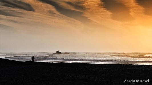 Paar steht bei Sonnenuntergang am Strand und betrachtet die Ruine eines Wachturms am Strand, Silhouetten, Essaouira, Marokko 2014