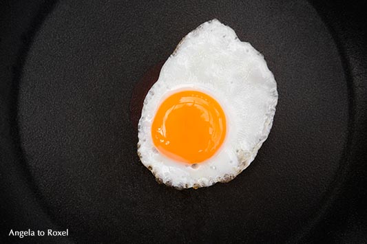 Food-Fotografie: sunny side up - gebratenes Wachtelei, Spiegelei in einer schwarzen Pfanne, von oben, März 2016 - Stockfotografie, Bildlizenz