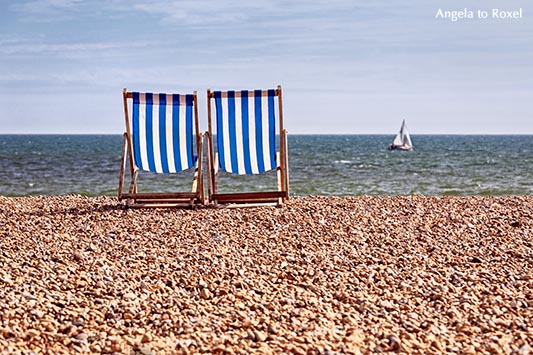 Fotografie: Zwei Deckchairs am Kiesstrand, im Hintergrund ein Segelboot, das über den Ärmelkanal fährt, Brighton, England 2014 - Stockfoto, Bildlizenz