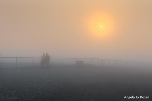 Paar auf der Nordkapp-Plattform beobachtet, wie die Mitternachtssonne durch den Nebel bricht - Norwegen 2014