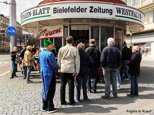 Clown steht in einer Warteschlange vor einem Kiosk am Jahnplatz, Spontanität an einem Samstag in der Bielefelder Innenstadt - Bielefeld, April 2016