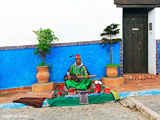 Gnawa-Musiker spielt auf der Sintir, vor einem blau und weiß gestrichenen Haus in der Kasbah des Oudaïas, Altstadt von Rabat - Marokko 2013