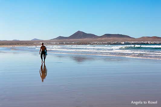 Famara Beach, langer weißer Sandstrand und Hotspot für Surfer auf Lanzarote, dahinter La Caleta de Famara und die Feuerberge | Angela to Roxel